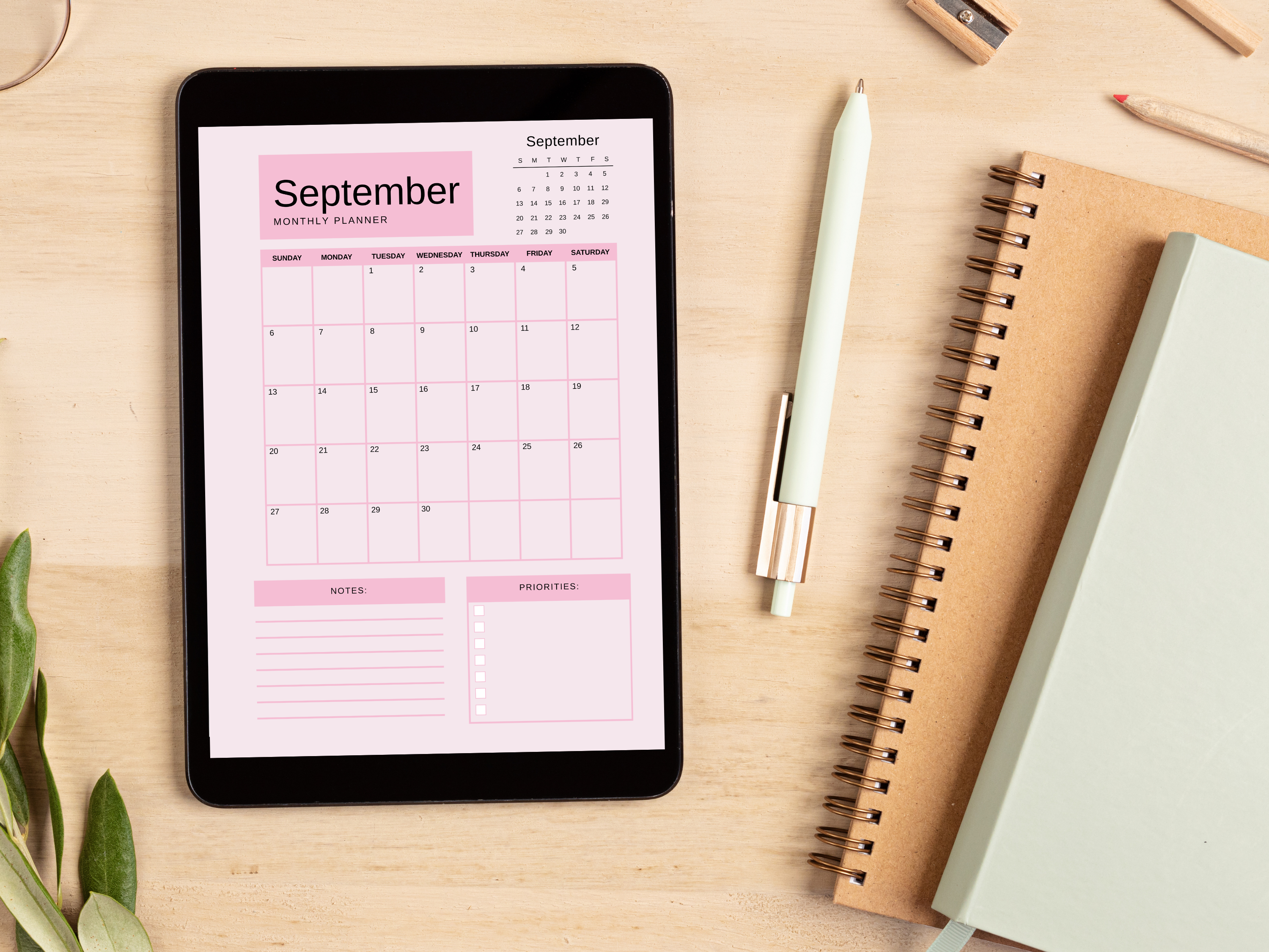 Digital tablet displaying a September planner on a wooden surface with stationery items.