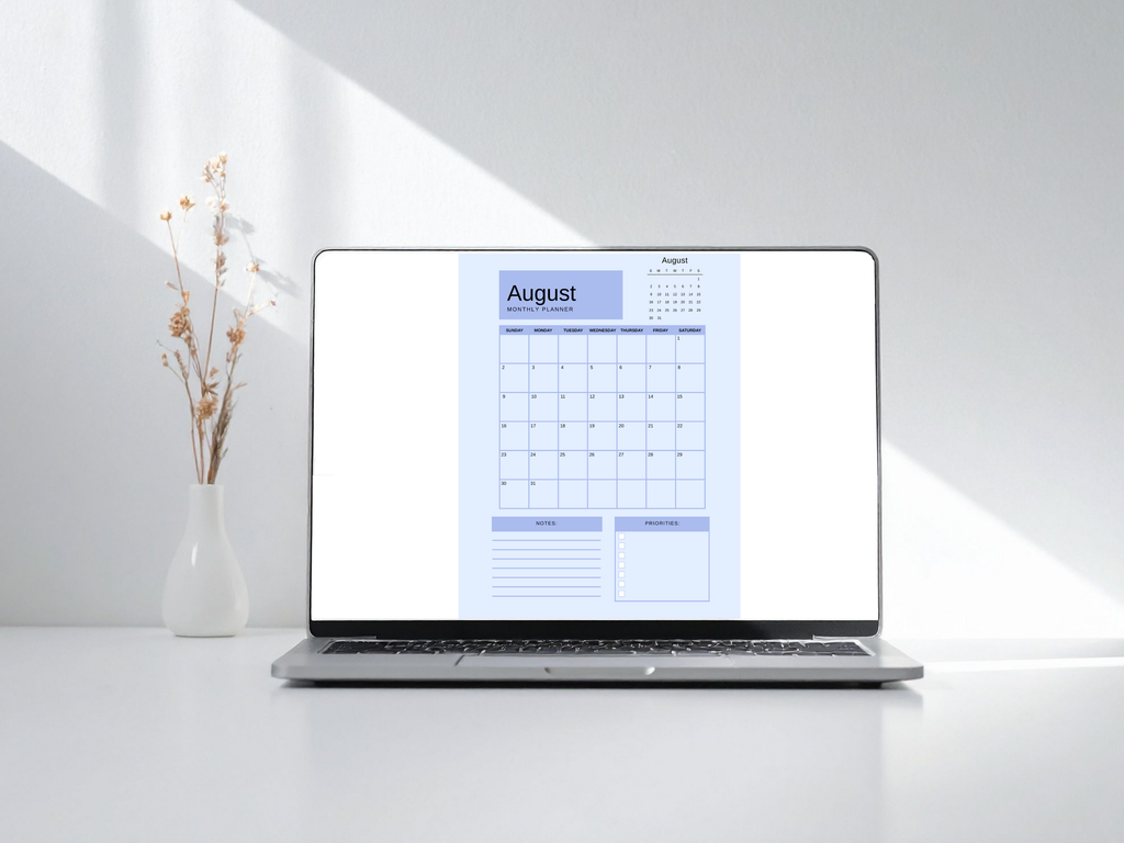 Laptop displaying an August calendar on a white surface with a vase of flowers.