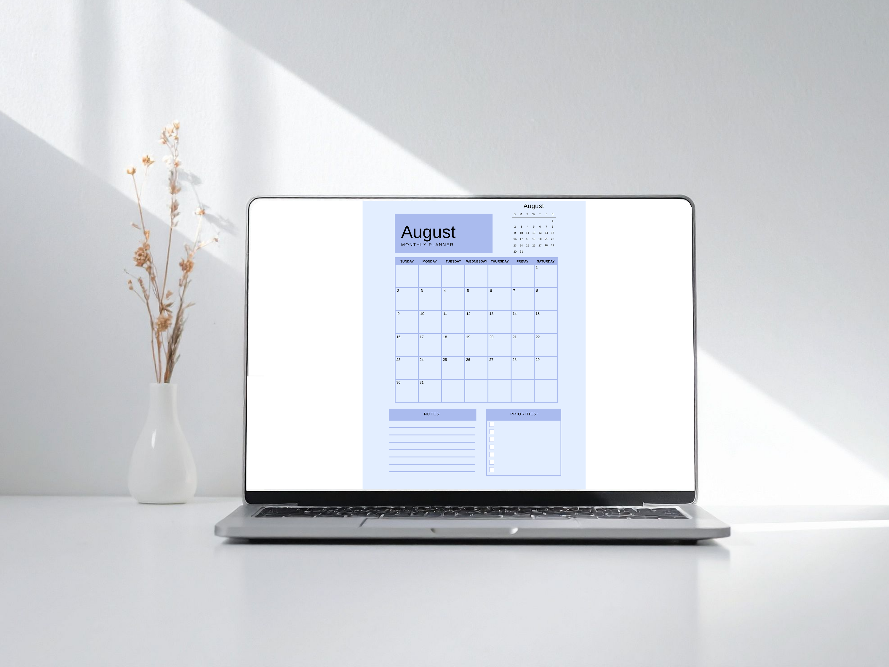 Laptop displaying an August calendar on a white surface with a vase of flowers.
