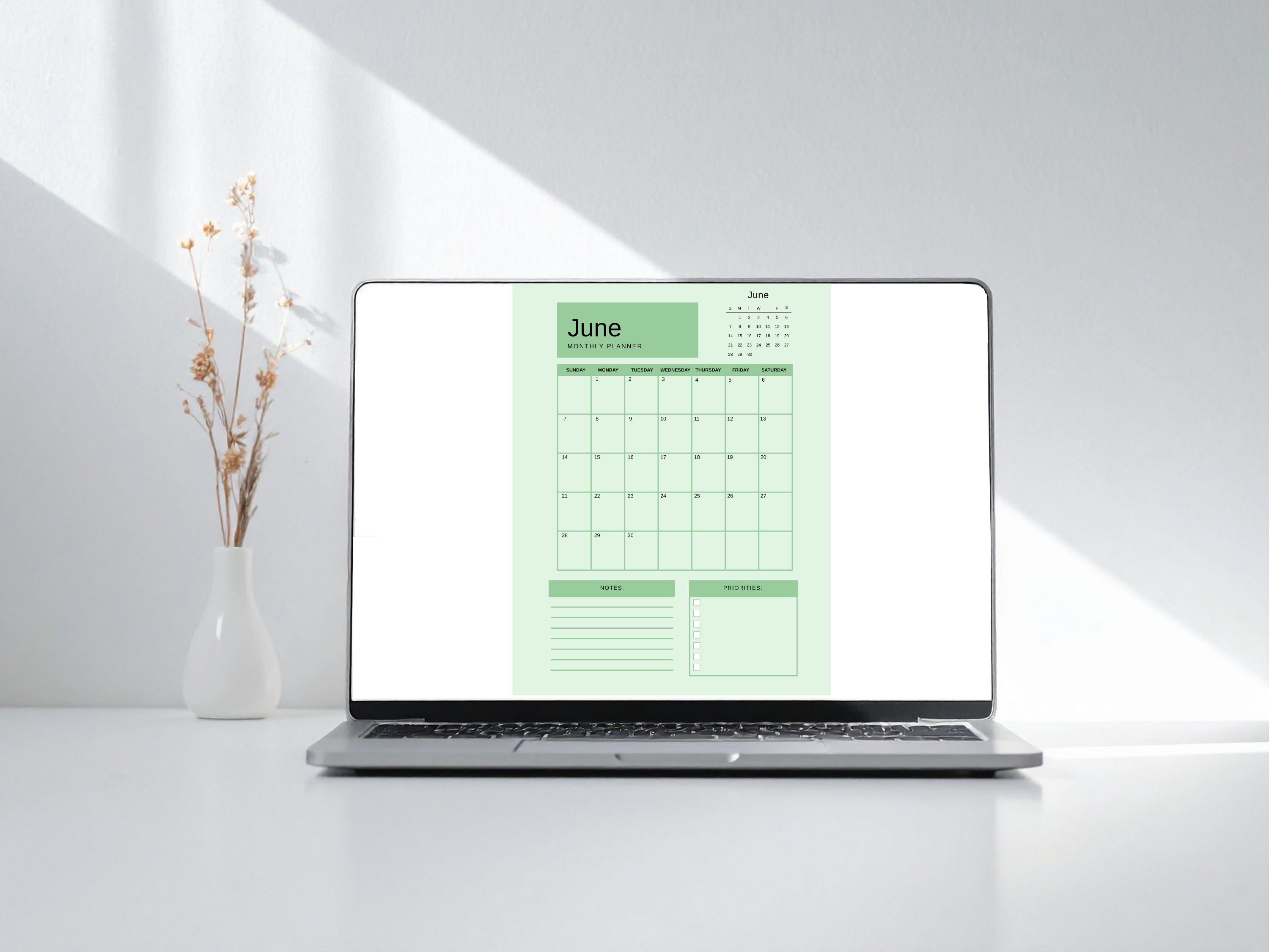 Laptop displaying a green calendar on a white background