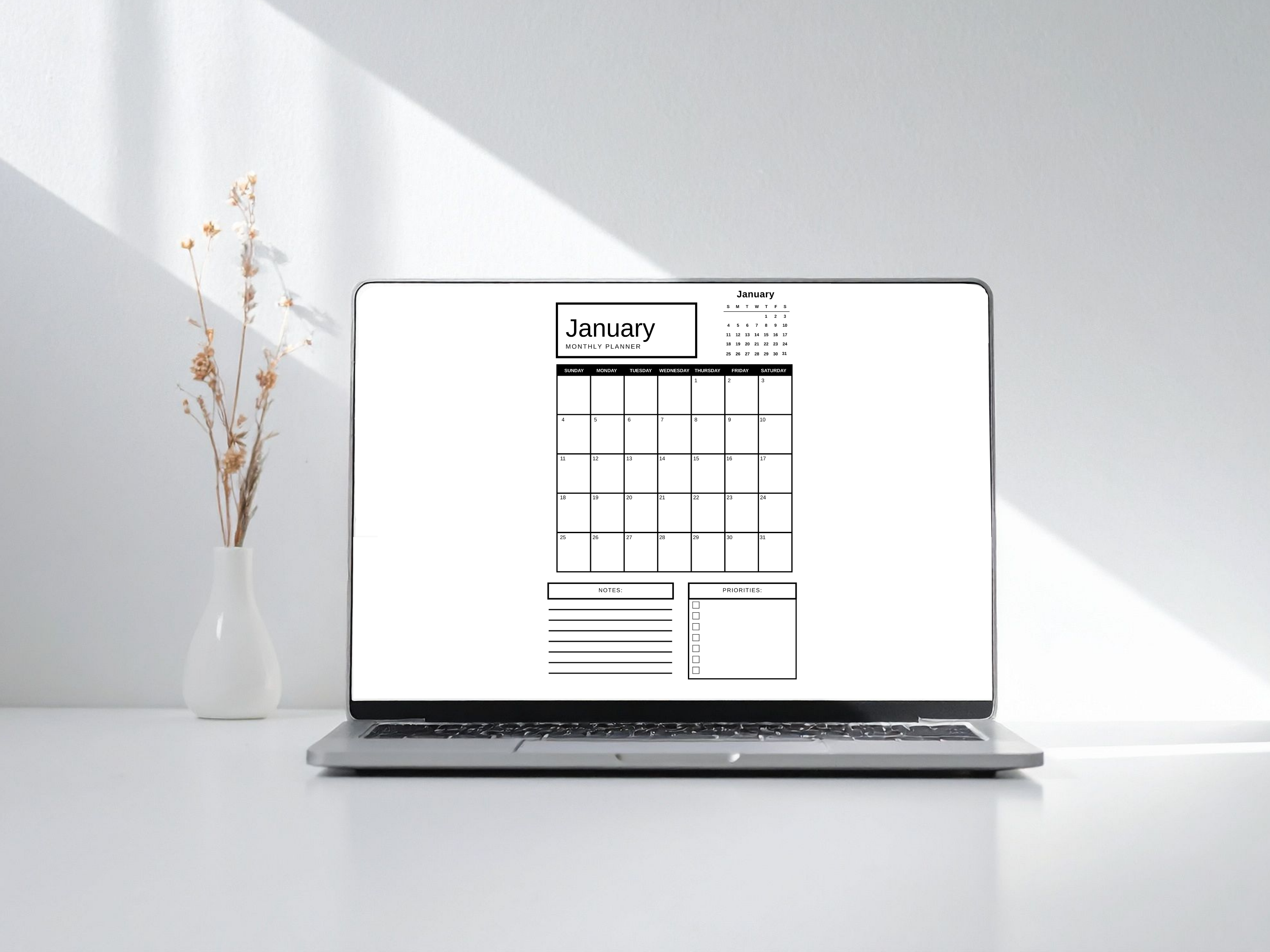 Laptop displaying a January calendar on a white surface with a vase of flowers.