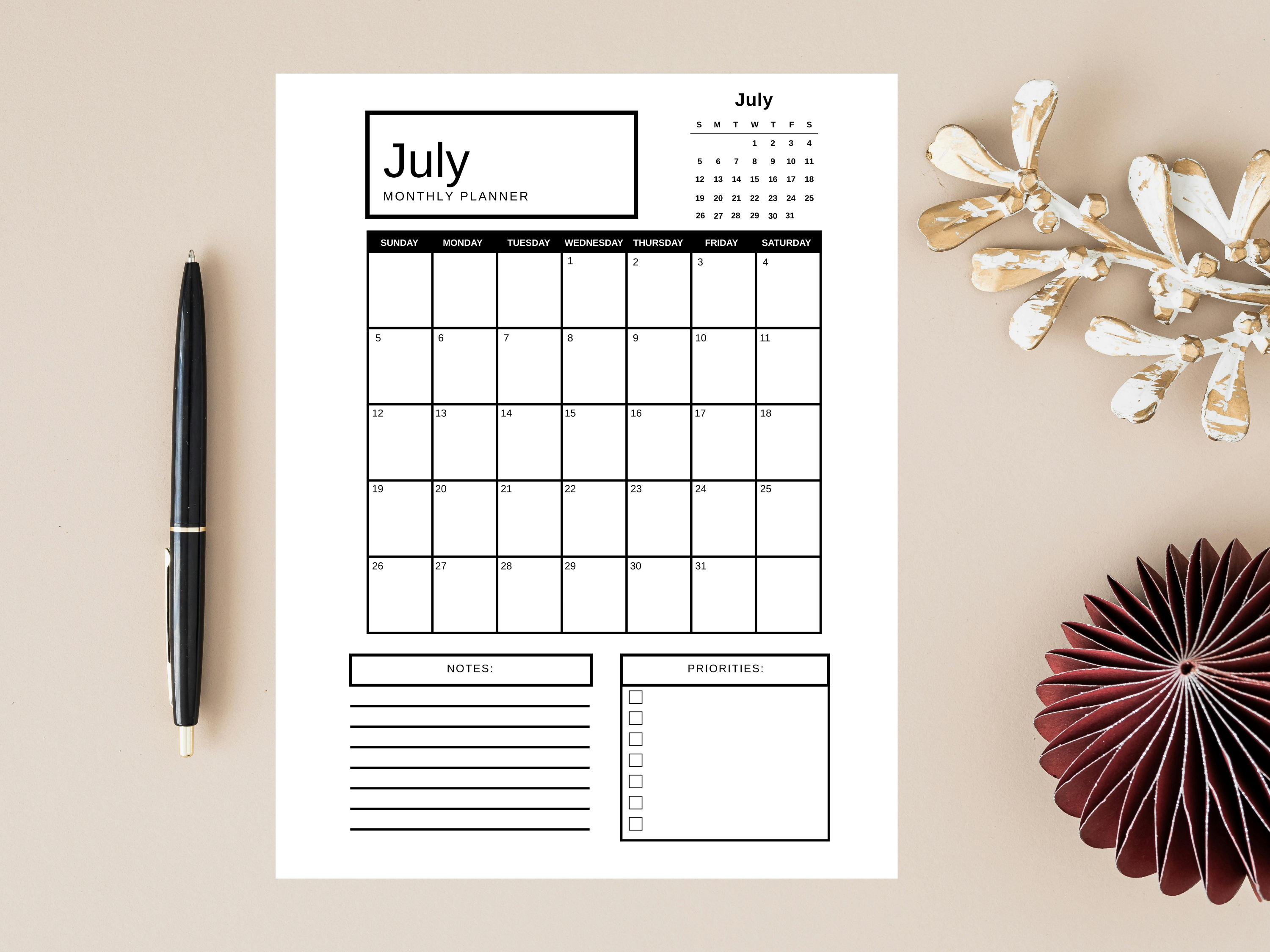 Calendar planner for July on a beige surface with decorative items.