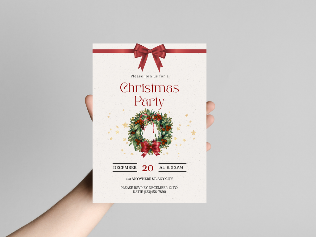 Hand holding a Christmas party invitation with a wreath and bow design on a gray background