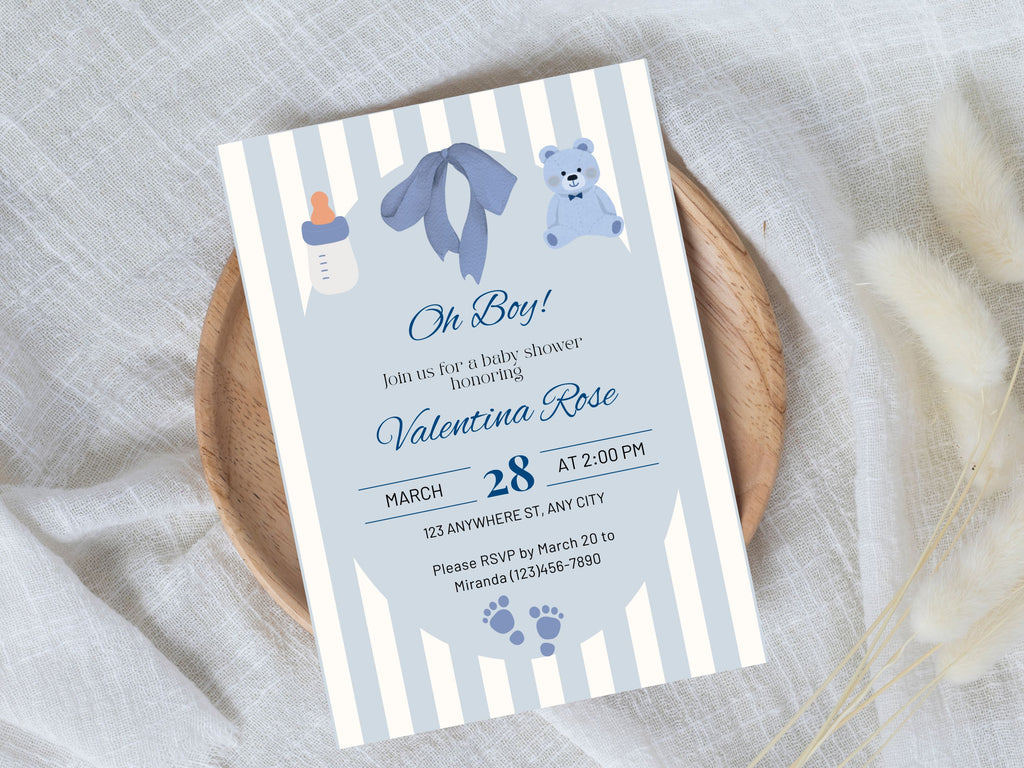 Baby shower invitation with blue and gray striped design on a textured surface