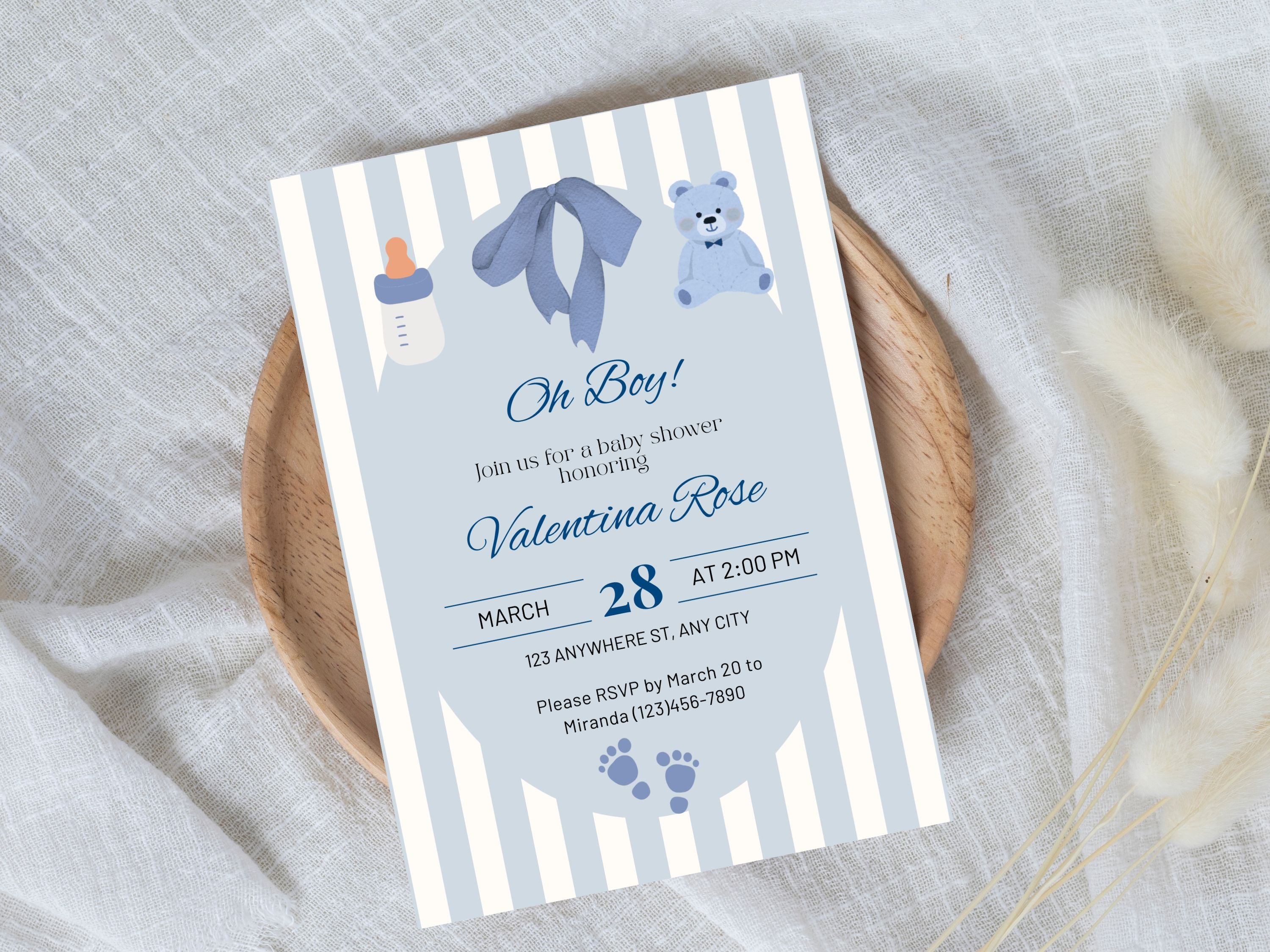 Baby shower invitation with blue and gray striped design on a textured surface