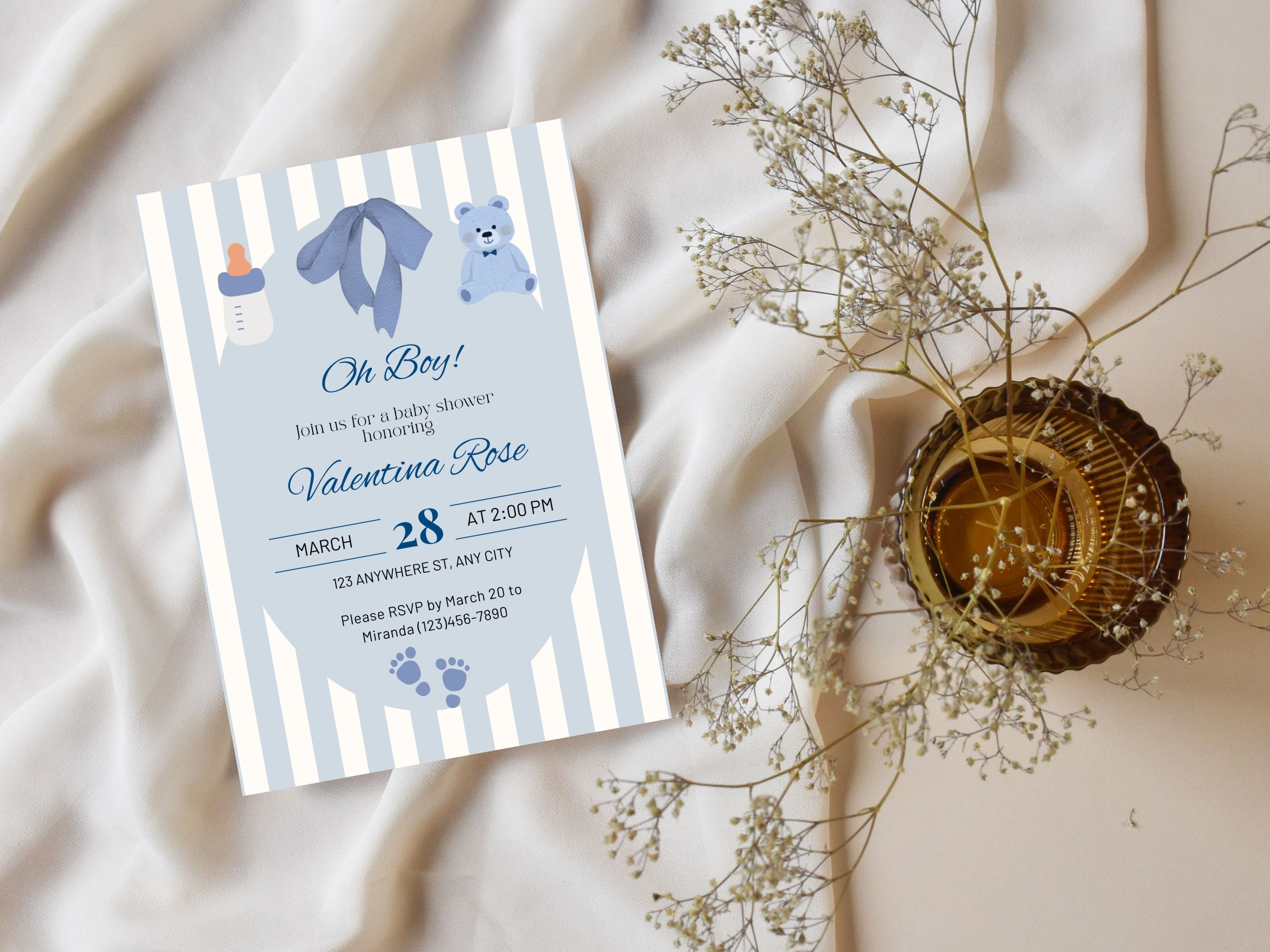 Baby shower invitation with blue and white striped design on a soft fabric background