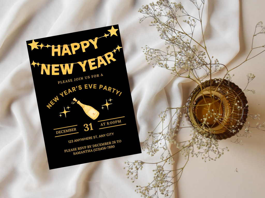 New Year's Eve party invitation card with gold text on a black background, placed on a soft fabric surface with decorative elements.